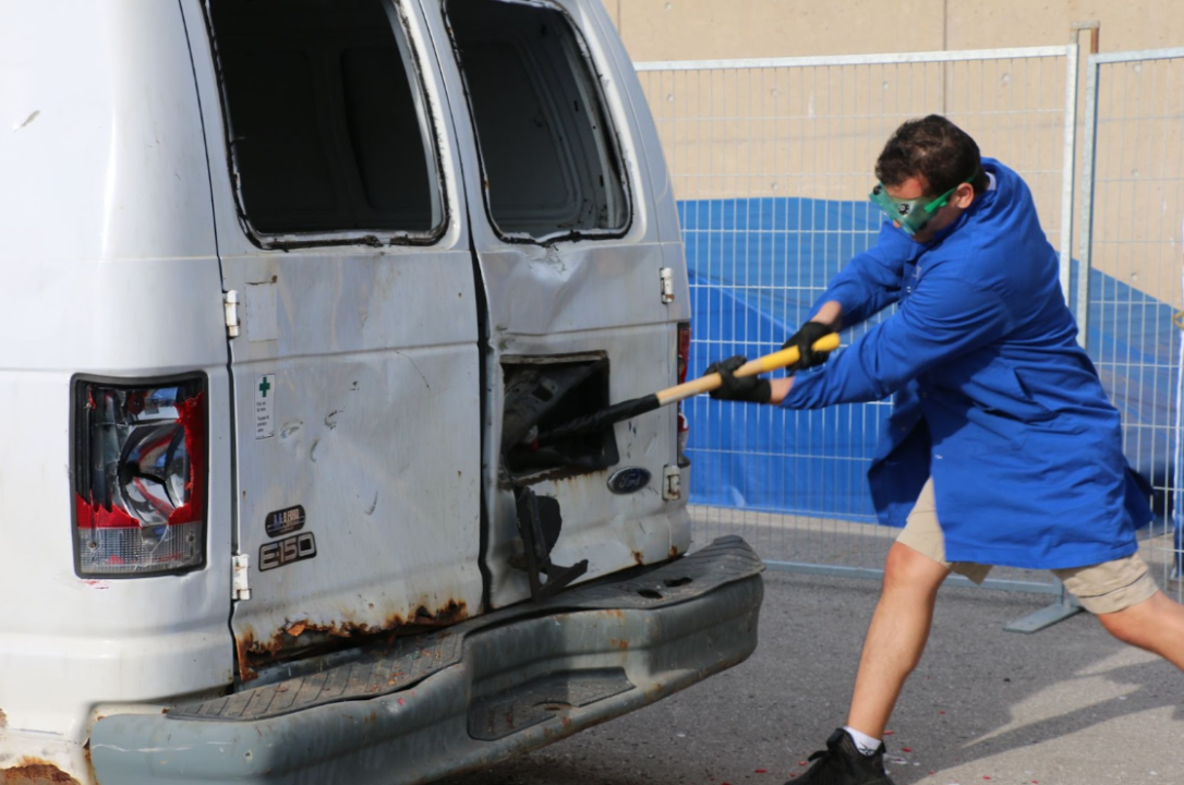 Student smashing a white van with a sledgehammer.