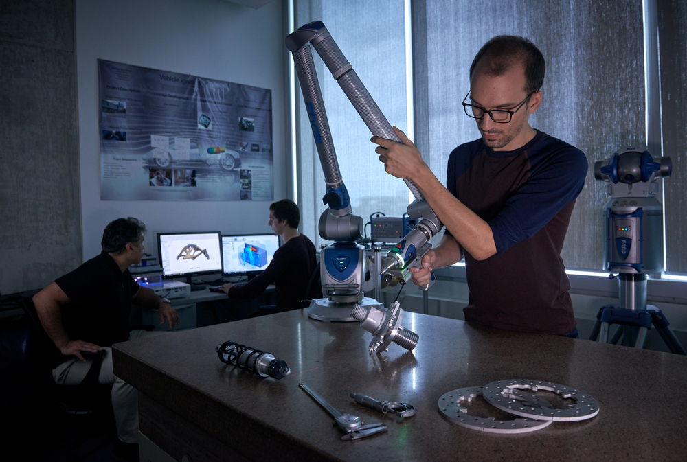 Student working on the development of a Scientific Instrument on a table in the Ahmad Barari Lab in the Faculty of Engineering and Applied Science with two other students in the background on their laptops.