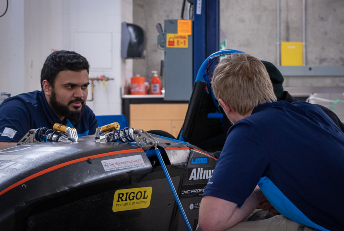 Two students beside the motorsport vehicle. 