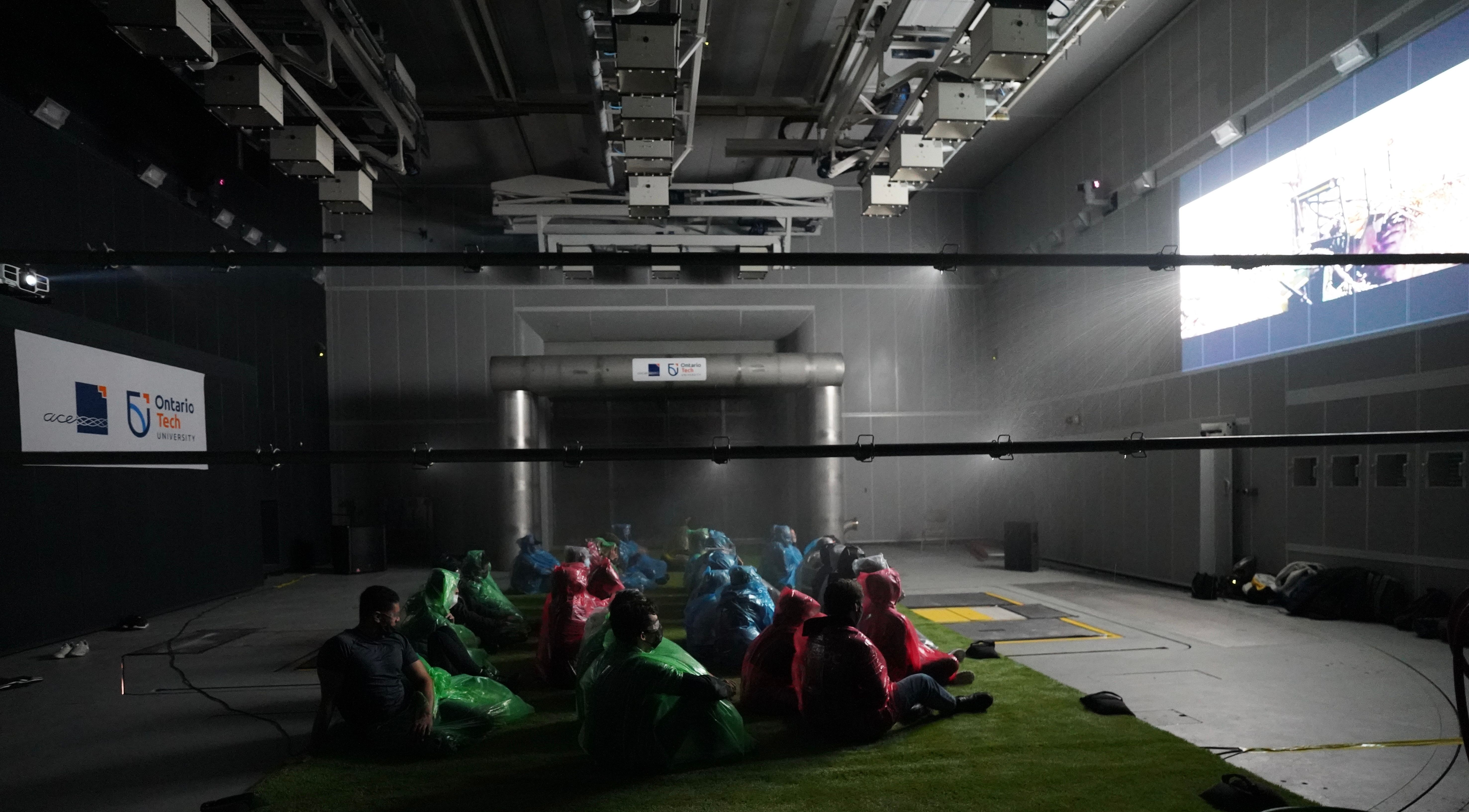Students are watching the Twister film, sitting in the climatic wind tunnel while water is sprayed on them. ${altNumber}