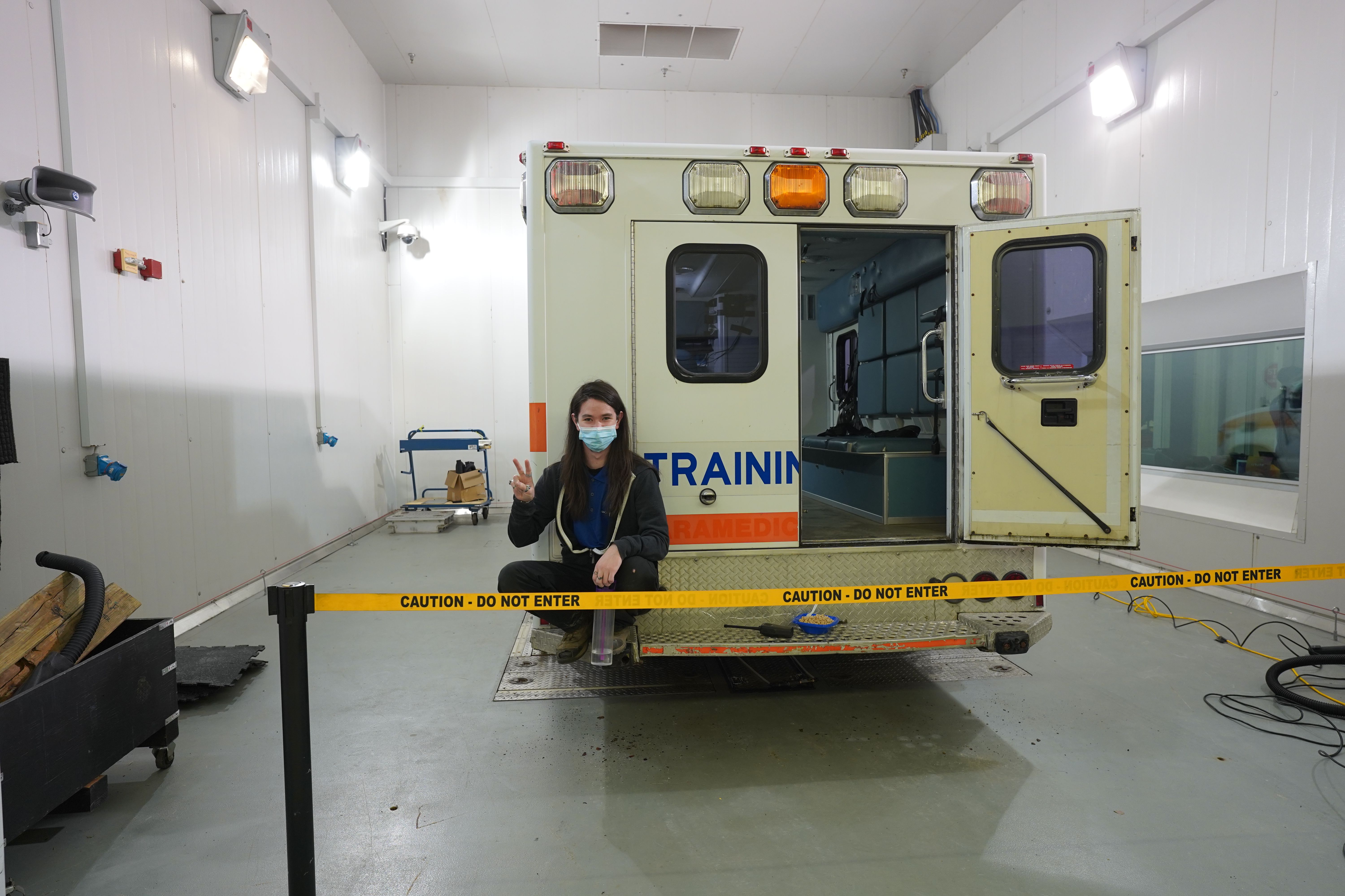 ACE student employee sitting in front of an ambulance with caution tape surrounding the vehicle.  ${altNumber}