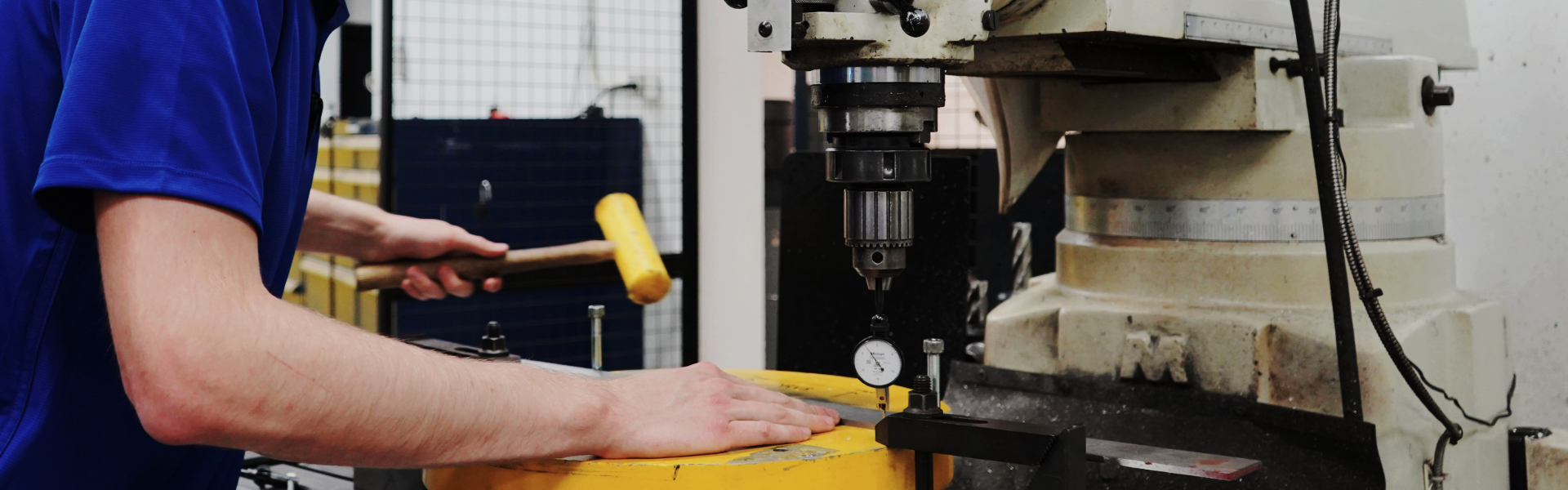 An ACE employee is using a piece of equipment in the machine shop.