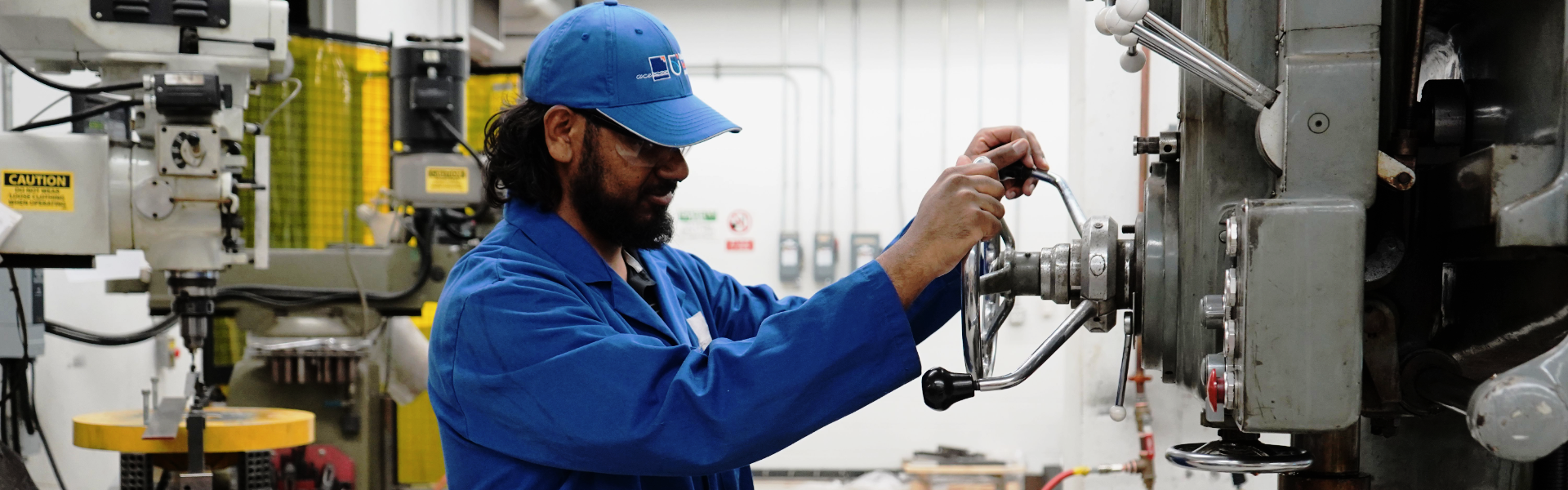 An ACE employee is using a piece of equipment in the machine shop.