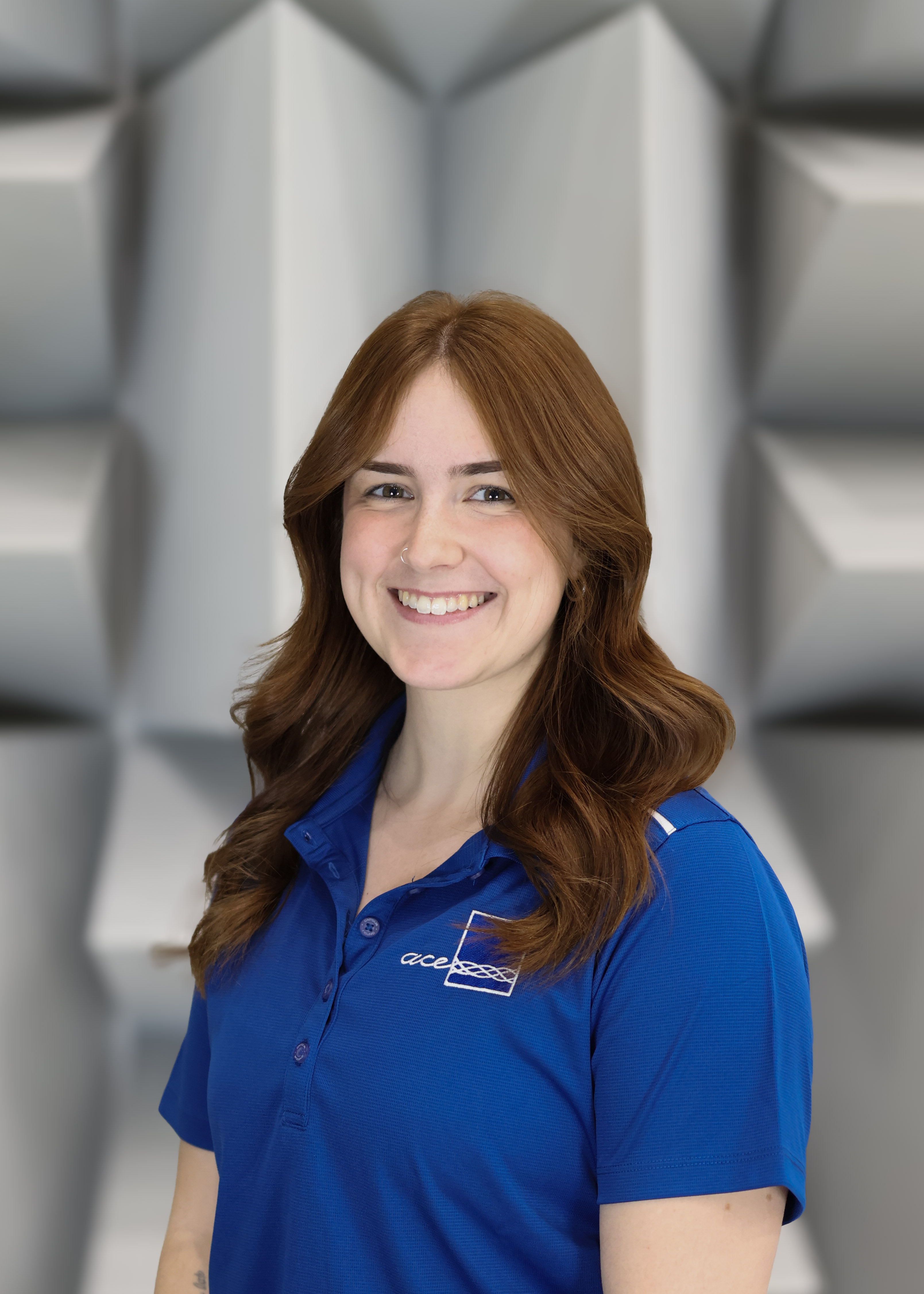 Headshot of ACE Ontario Tech R&D Engineer Eric Whalls in ACE and Ontario Tech University branded blue polo in hemi-anechoic chamber