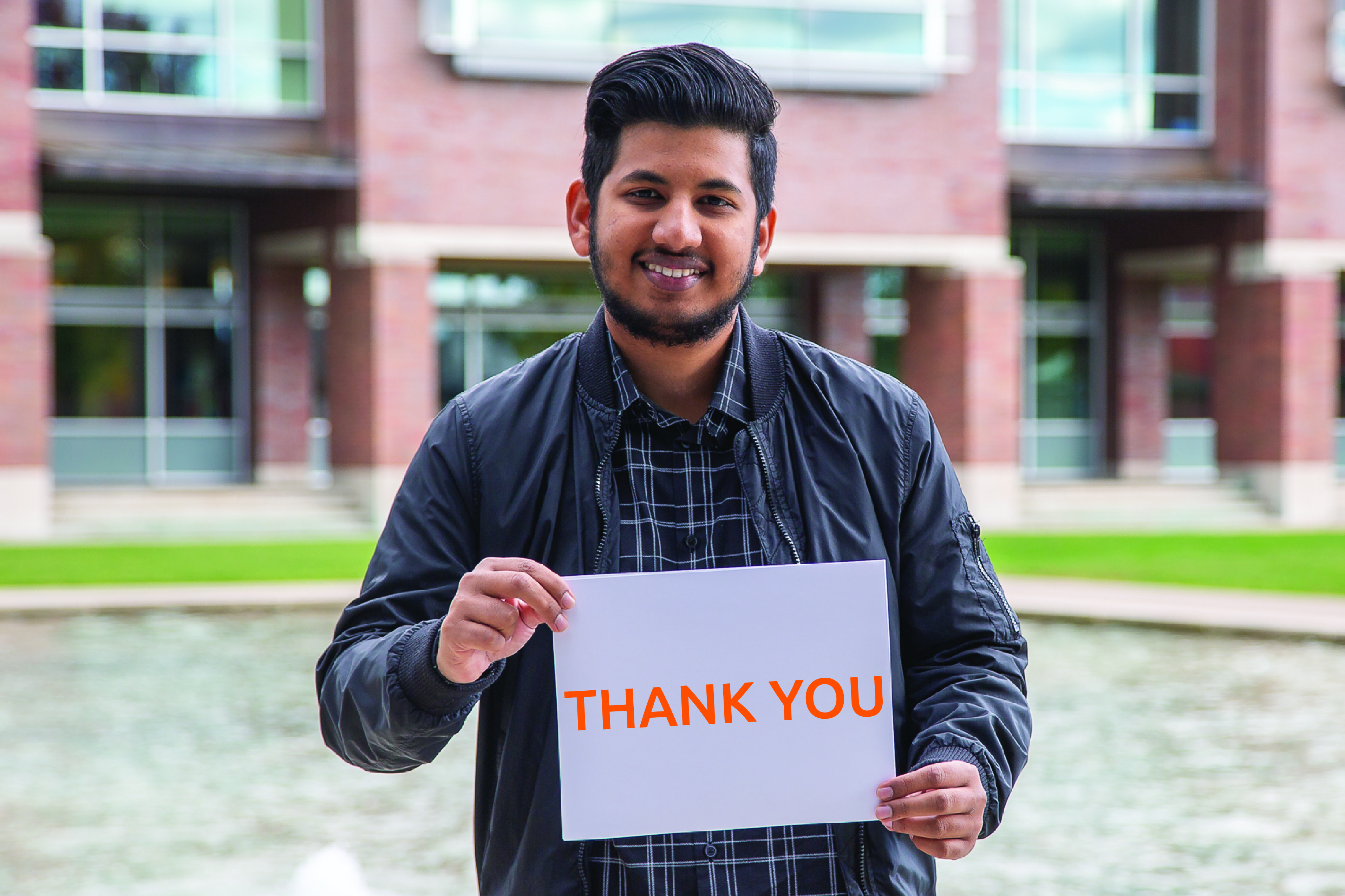 A male student holding a Thank You sign
