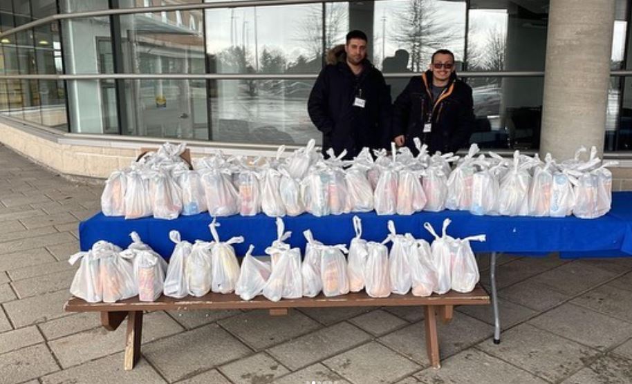 Two volunteers hand out free Ramadan meals to students.