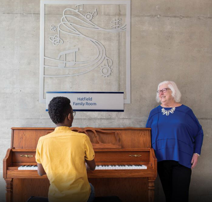 Lynda C. Hatfield with Evans Mosomi, Software Engineering, class of 2022, enjoying the piano in the Hatfield Family Room