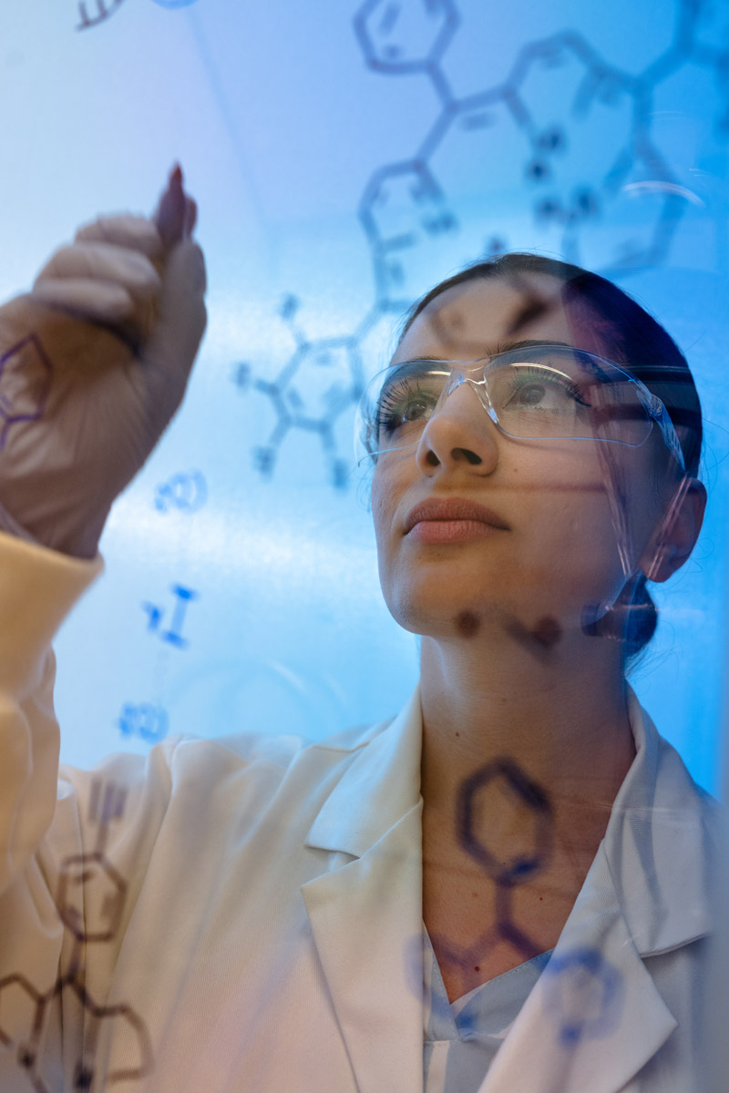 Chemistry student writing on a glass wall