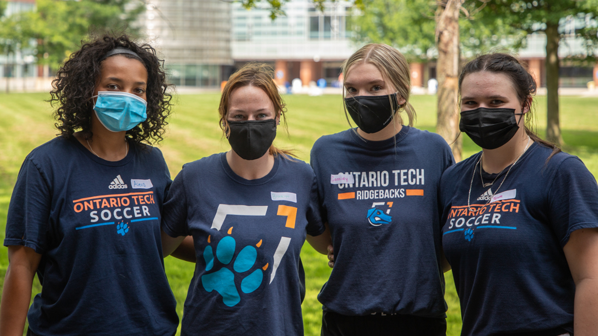 students wearing masks and ridgebacks shirts stand on polonsky commons