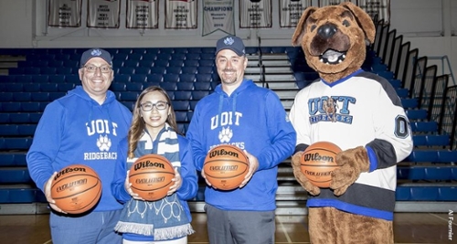 Faculty, student and Hunter the Ridgeback holding a basketball in the gym