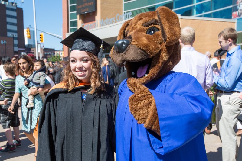 Graduating student and Hunter the Ridgeback taking a picture