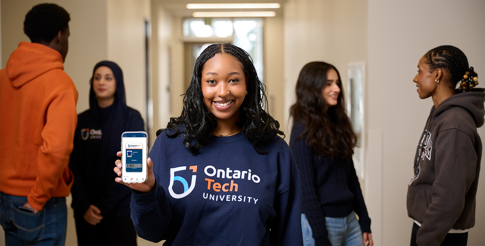 A student is showing Ucard on her phone with other students talking in the background