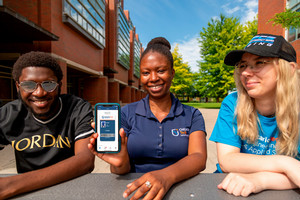 Photo of three individuals with one showing their digital Ucard