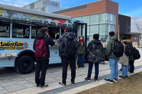 blue bus with students standing around it