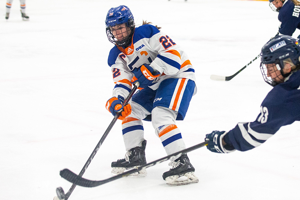 member of the Ridgebacks women's hockey team stickhandles a puck against a defender from an opposing team. 