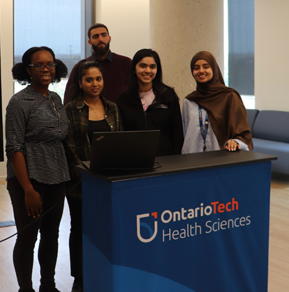 Group of five students standing behind an 鶹ý Health Sciences podium at an event or presentation.