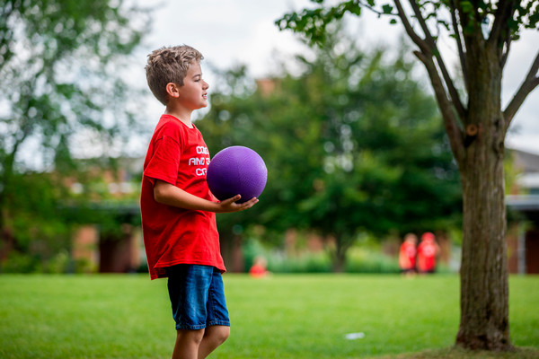 A camper holding a dodgeball outside at 2023 Summer Camps.