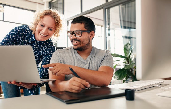 2 people pointing at a laptop