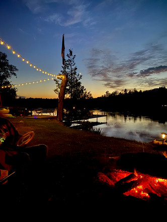 A picture of a bonfire behind the cottage, next to a water body.