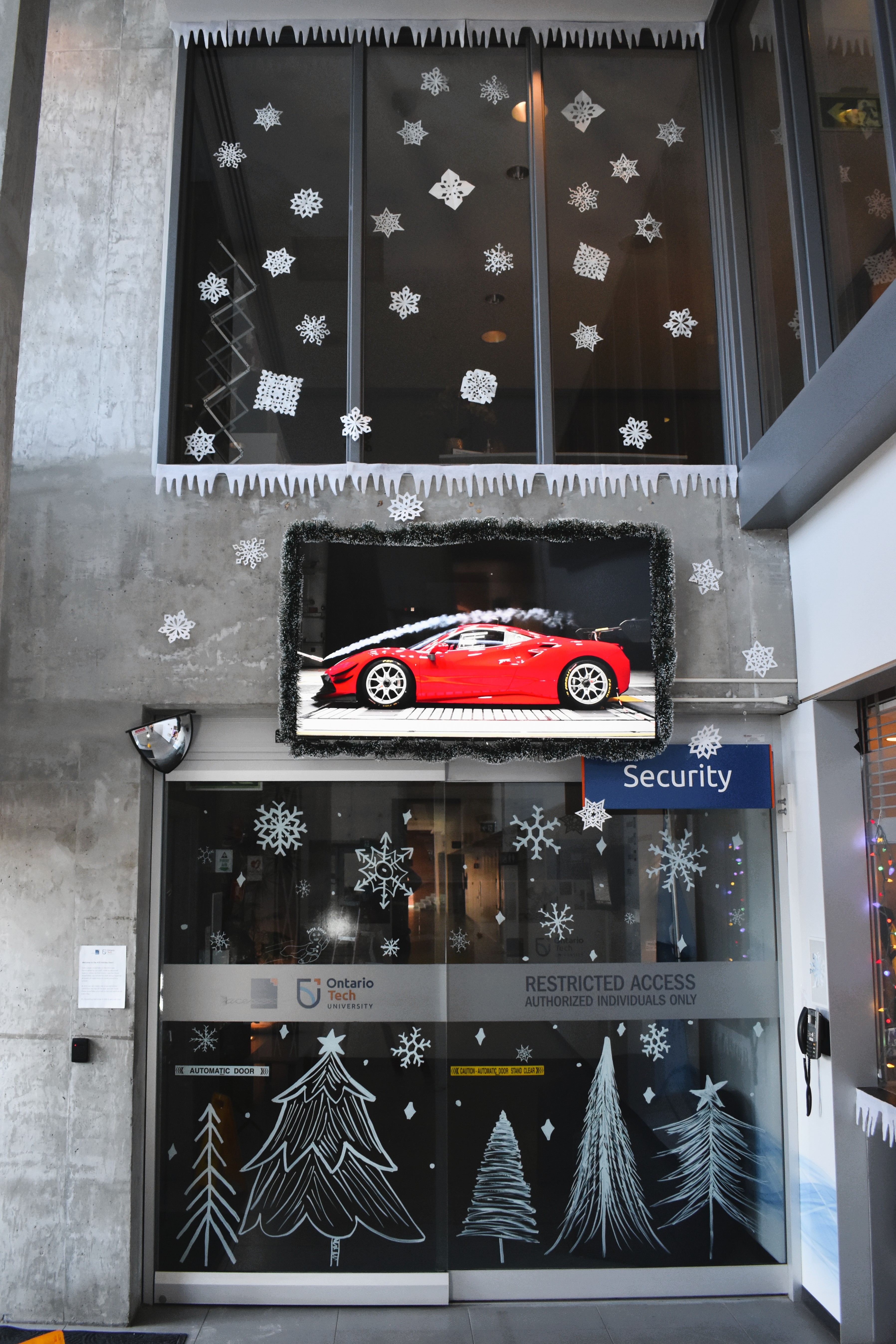 Decorated entryway featuring a red sports car displayed above a glass door adorned with a snowy, winter-themed design.