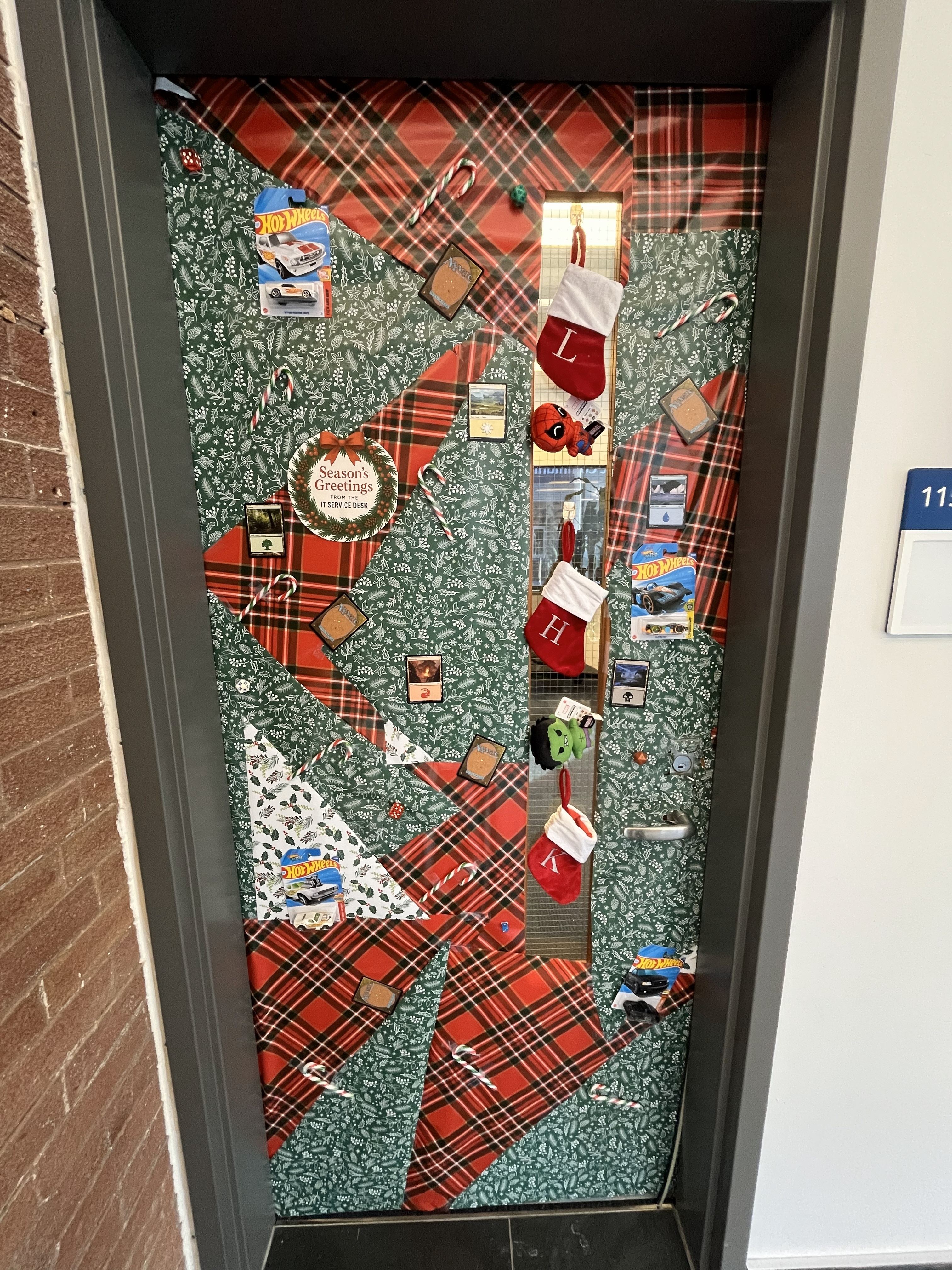 Decorated door with a festive plaid design, featuring holiday decorations including stockings, candy canes, and various themed ornaments.