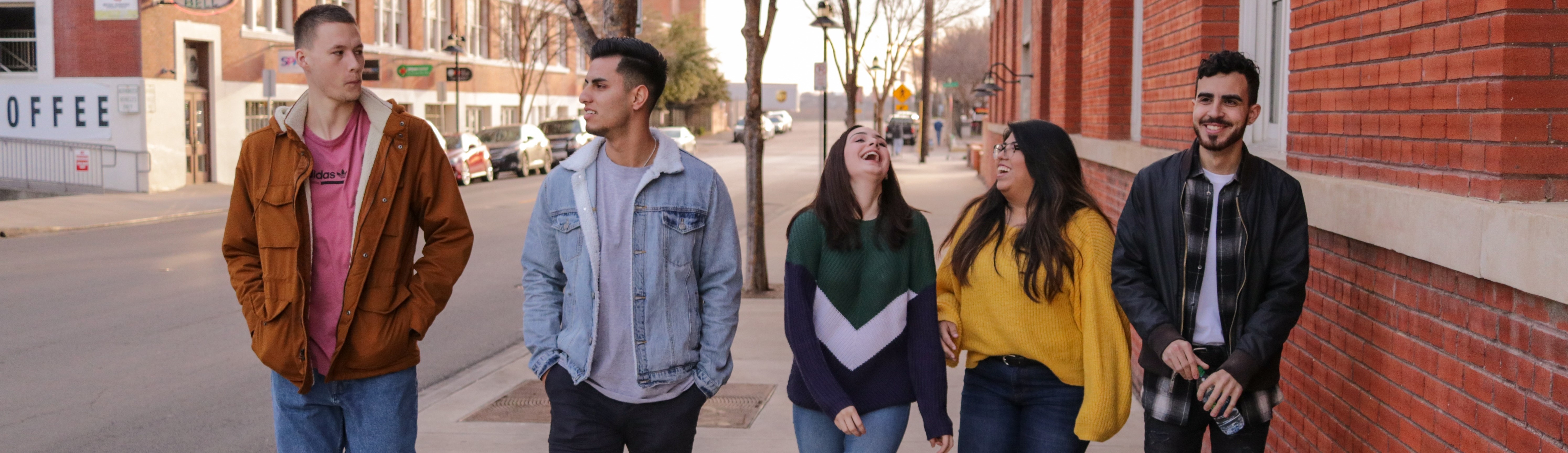 Five students walking along a city street. Photo by Eliott Reyna on Unsplash.