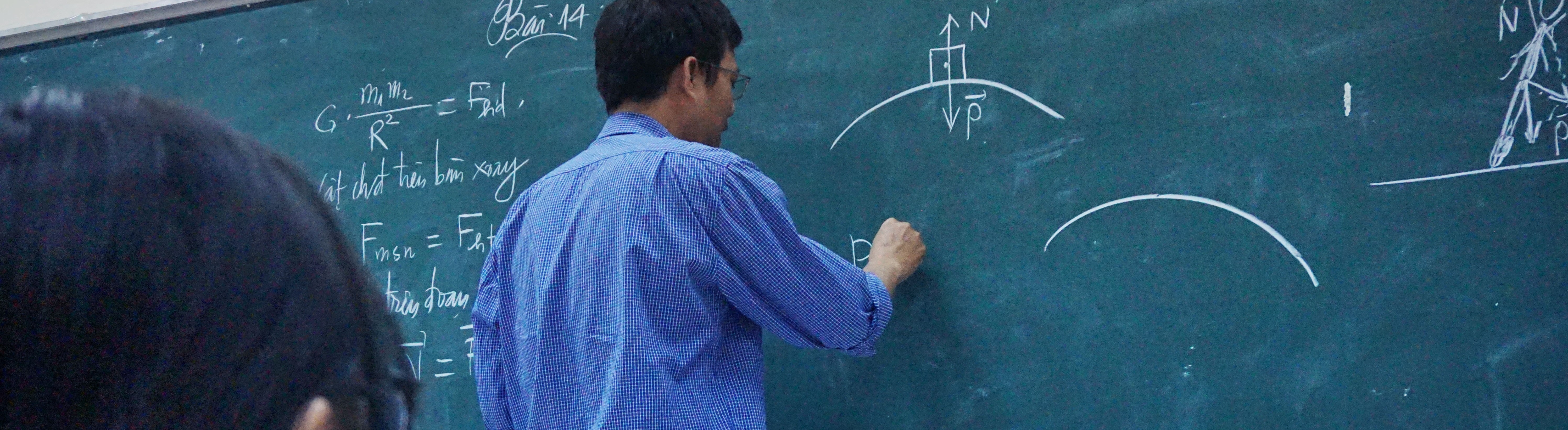 Photo by Tra Nguyen on Unsplash. A professor writing a math equation on a chalkboard