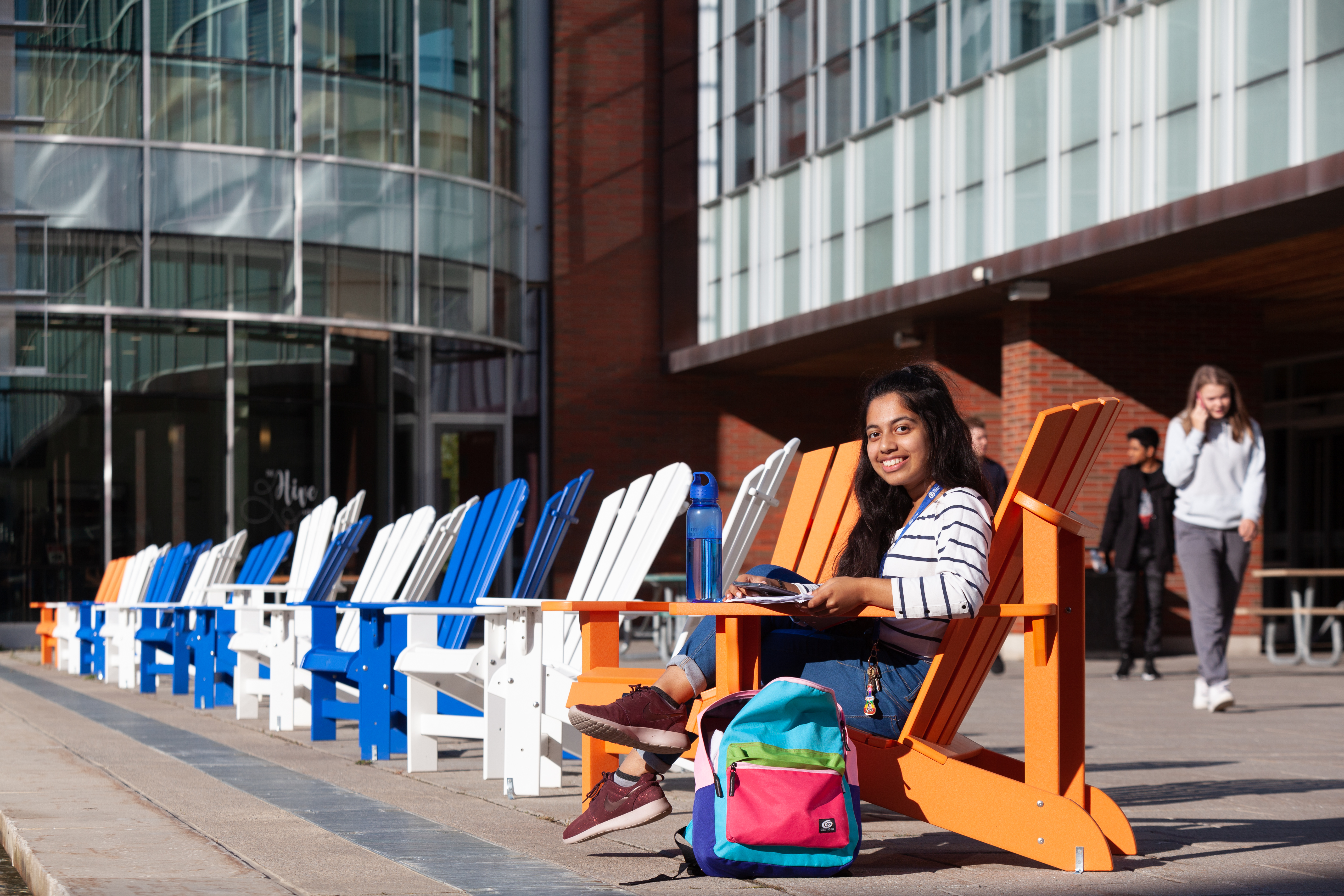 student sitting in muskoka chairs outside the library