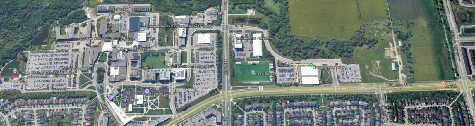 Aerial view of a campus layout featuring buildings, parking areas, and sports fields surrounded by greenery.