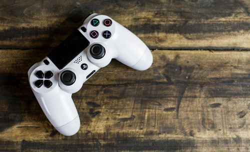 A videogame controller sits on a wood table.