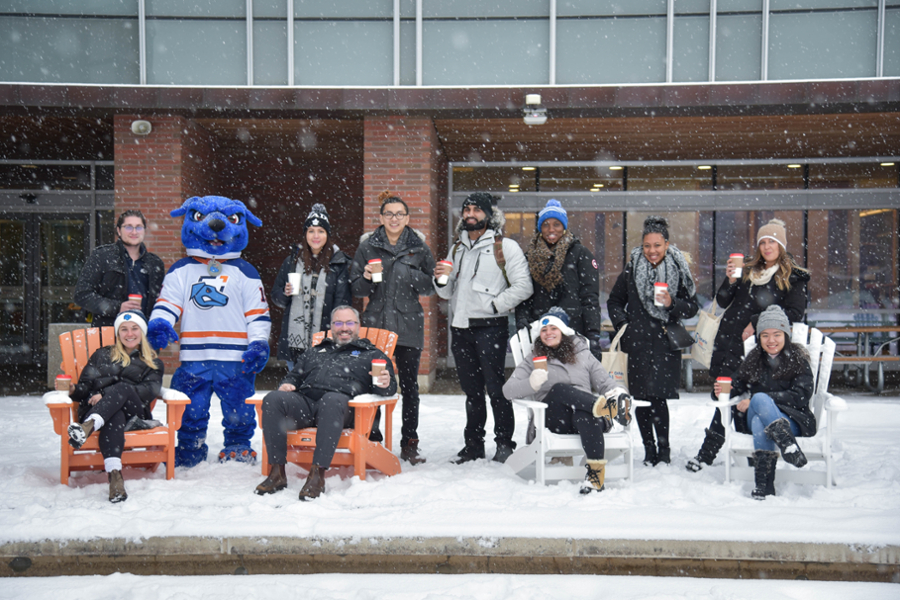 President Steven Murphy with 鶹ý University students and Hunter the Ridgeback in front of the North Oshawa Campus Library in the winter.