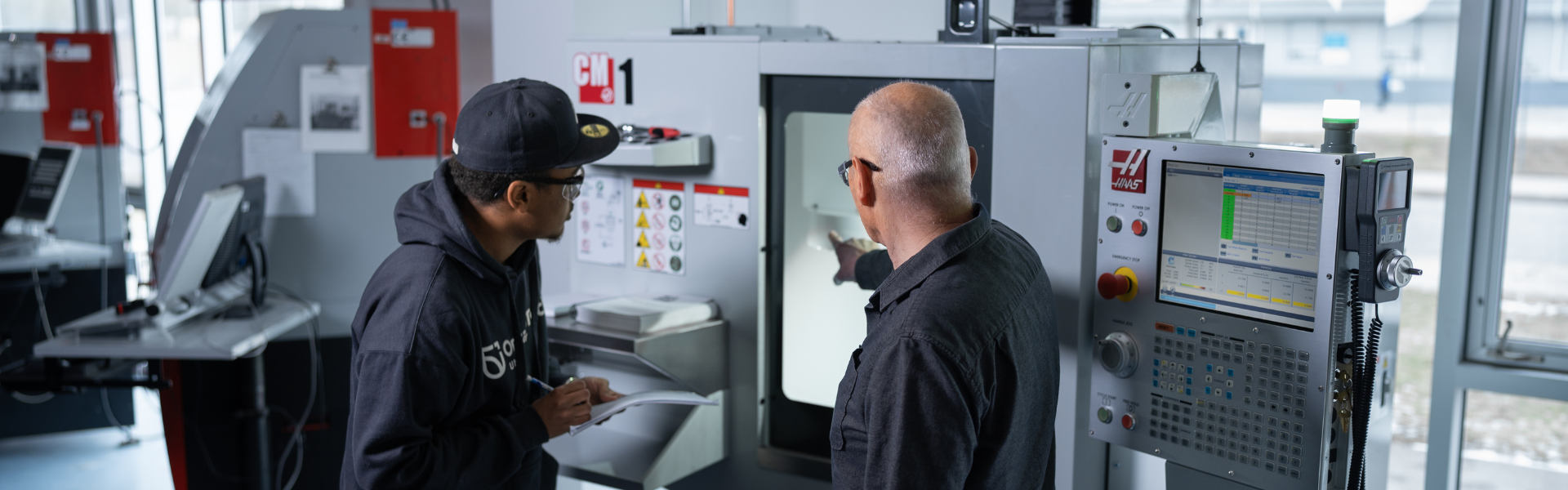 Male professor assisting male student in manufacturing engineering lab