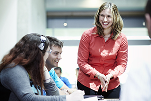 A female instructor smiles as she engages with two seated students