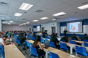 students in a traditional lecture hall with professor at front