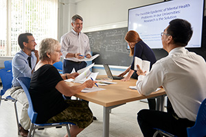 group of five around a table with papers