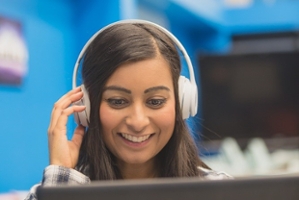 Female student with headphones looking at a computer