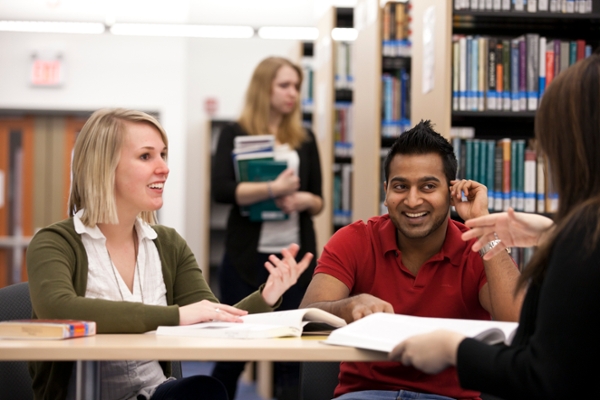 A group of students with open textbooks talk with each other