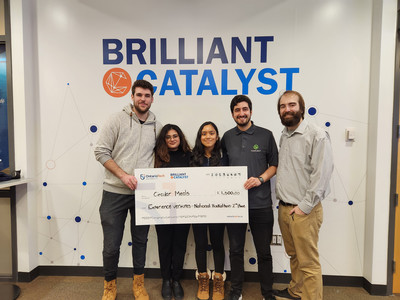 A group stands in front of the Brilliant Catalyst logoed wall holding a large cheque while smiling