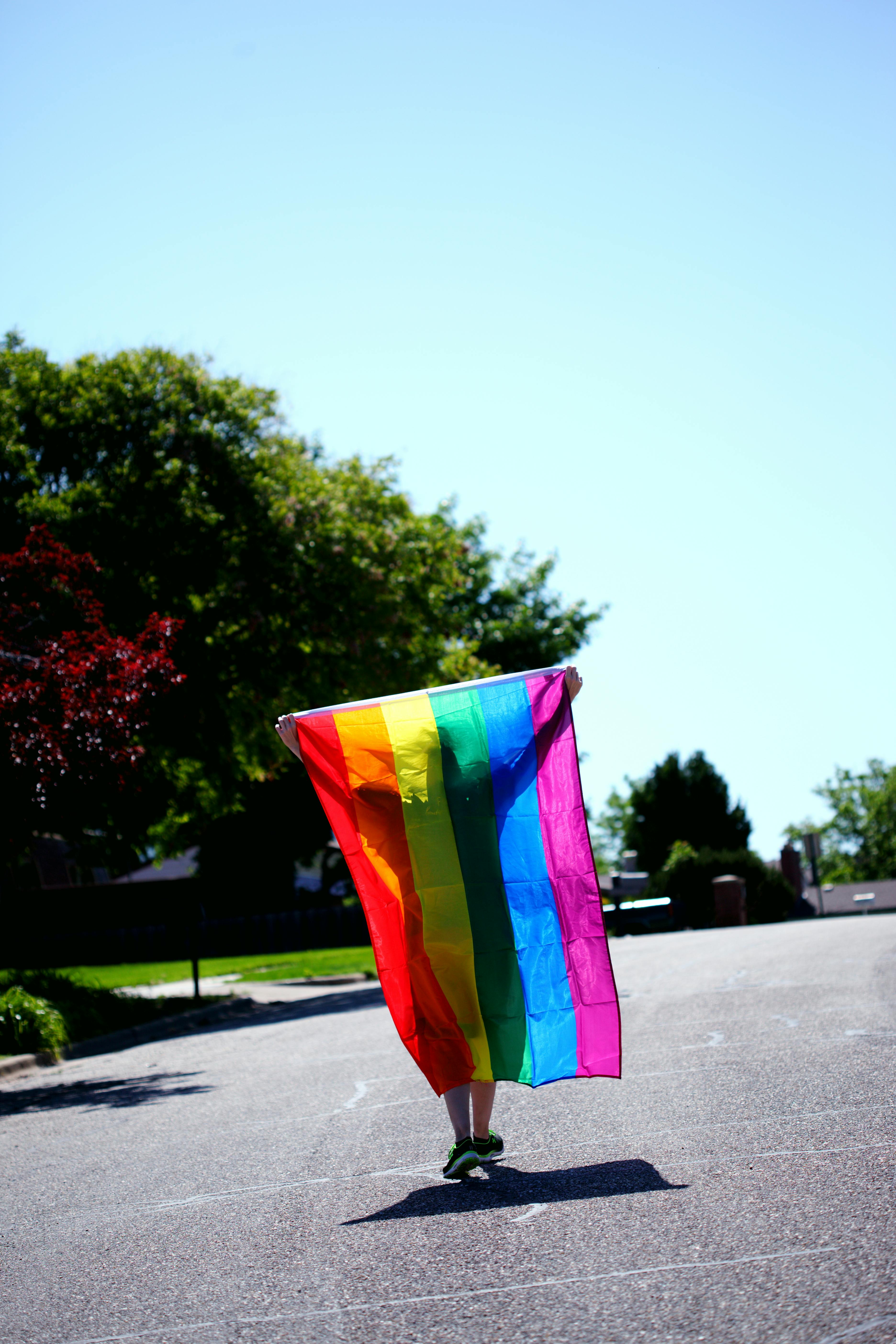 A person holding a rainbow flag for Pride Month