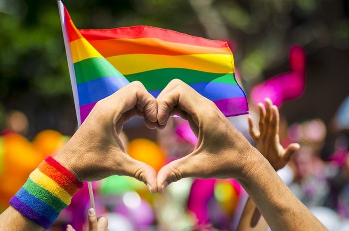 Pride rainbow flag and heart hands