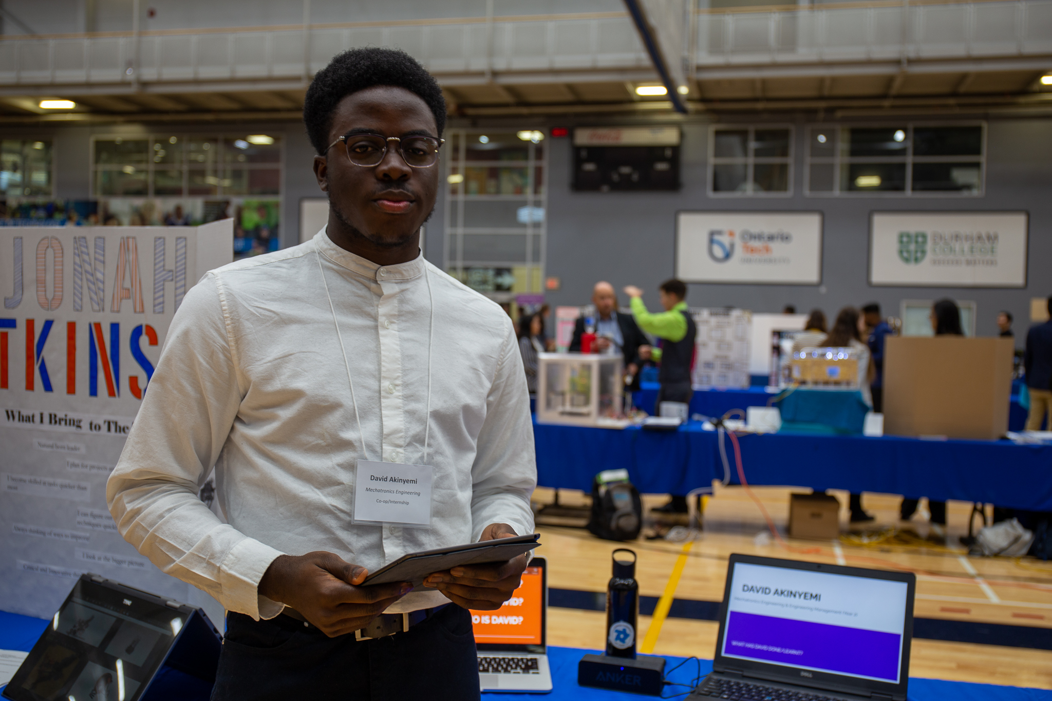 Student standing in front of a booth displaying work