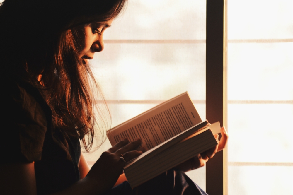 girl reading in front of window