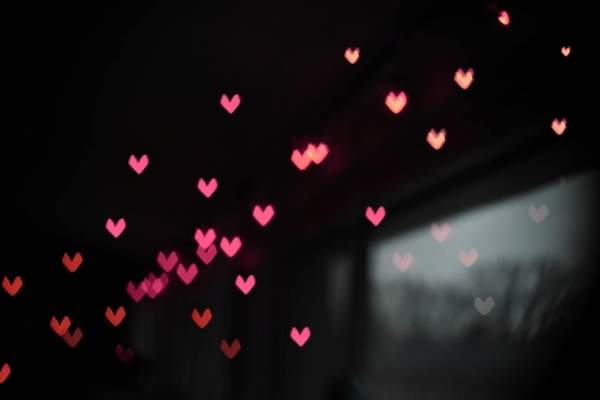 Several pink hearts with a black background. 