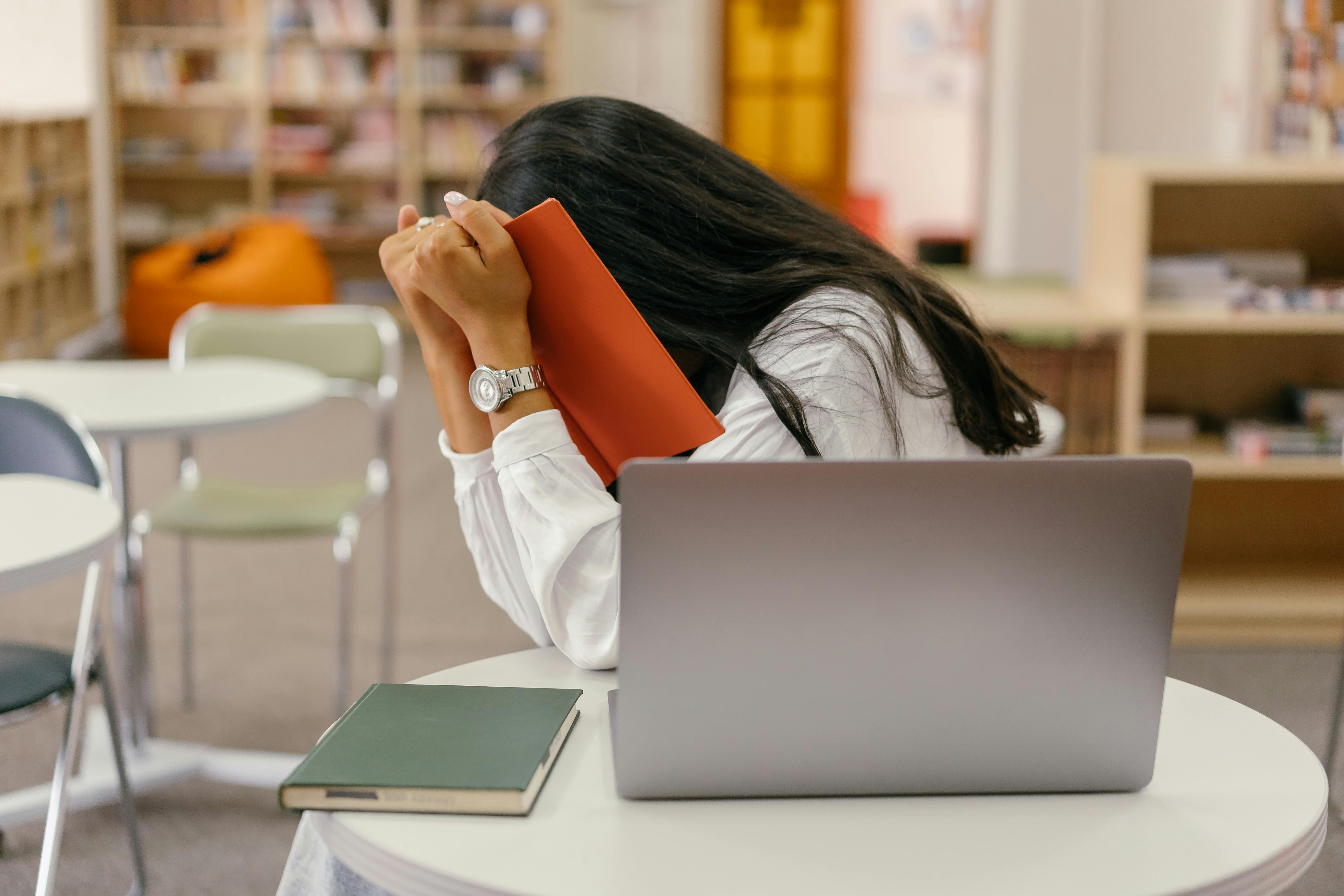 a student covering their face with a book 