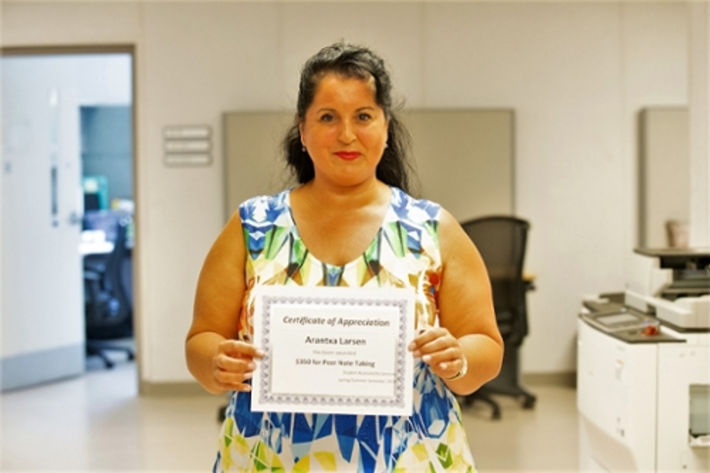 Volunteer note taker holding a certificate of achievement  