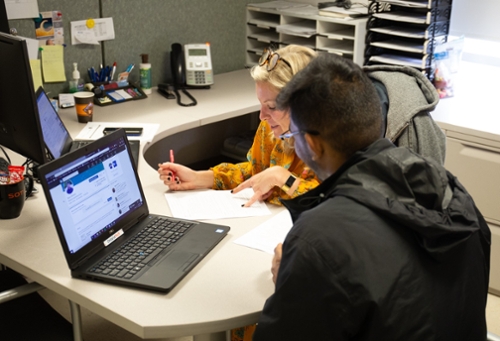 An employer sitting at a desk talking to a student about their LinkedIn profile.