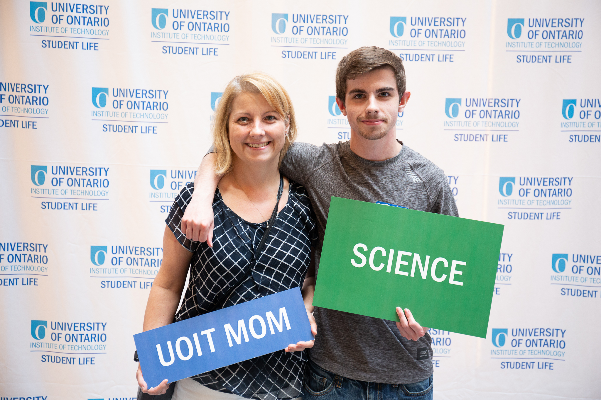 Student and mother holding science and uoit mom signs