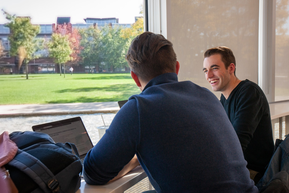 Two students working together on laptops.