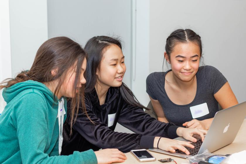 3 female students seated around a computer