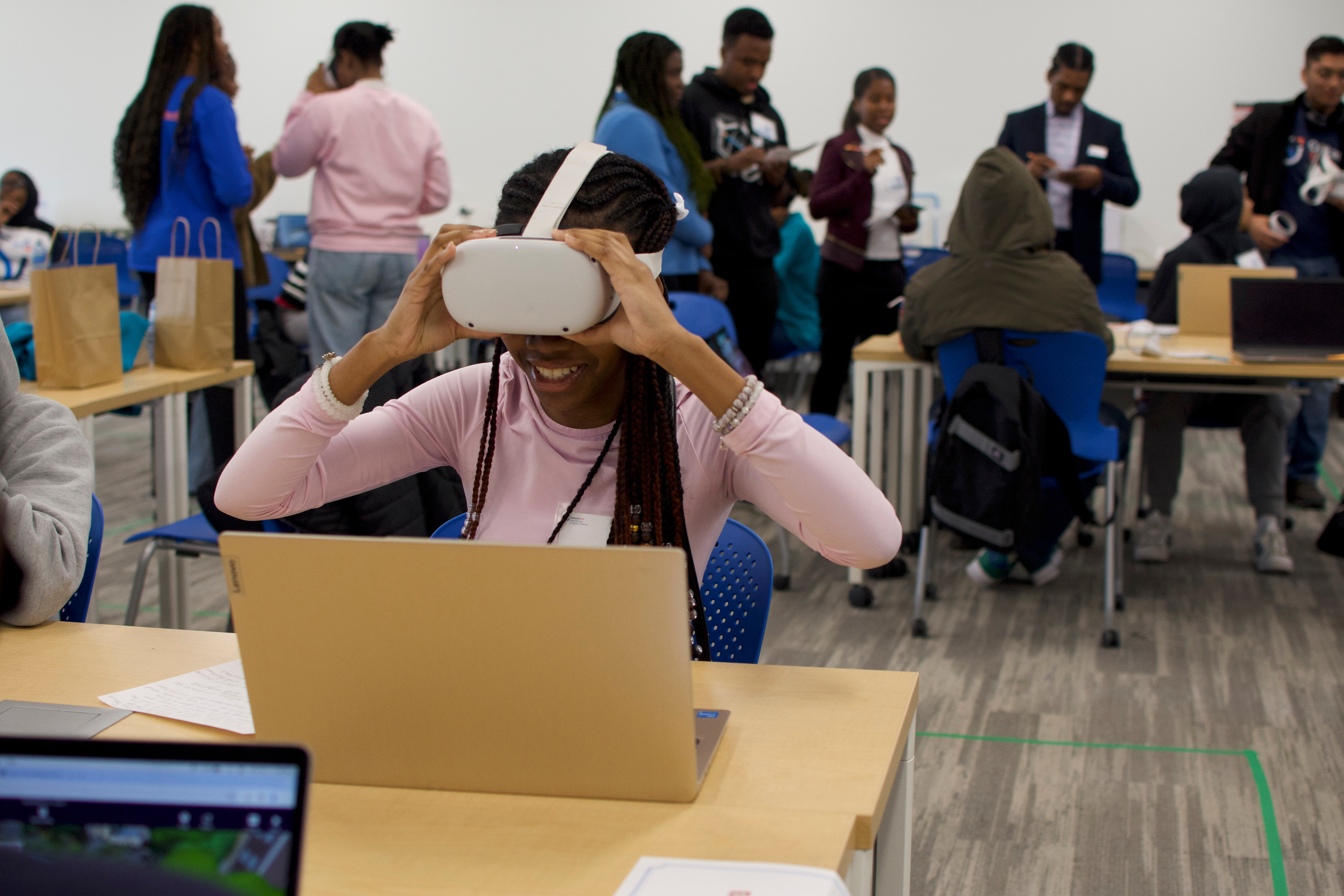 a girl sititng at a desk using a VR headset